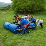 school pupils making a wooden raft from plastic barrels and wooden logs