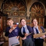 school pupils inside a church with clip boards and pencils