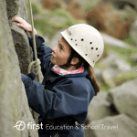 school pupil climbing up a cliff face