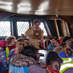 primary school pupils with tour guide learning about the sea ship the golden hinde
