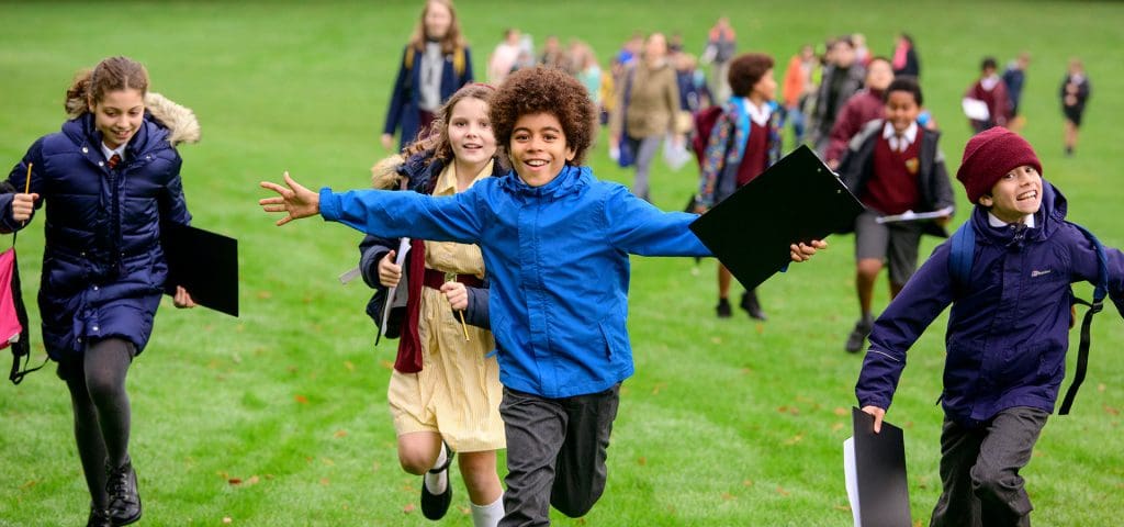 secondary school group on a trip running in a field