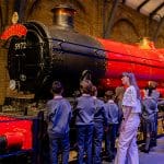 school group looking at a steam train and station
