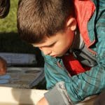 primary school trip student looking at a white examination tray with river water in it