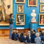 school group with museum tour person showing art work