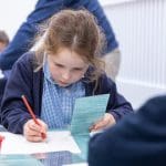 school pupil with paper and crayons drawing at workshop
