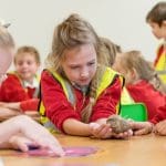 school pupil in a study class holding a very large snail