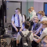 school group playing on video game consoles at a museum