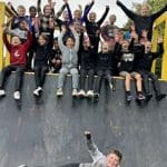 school group waving for a group photo sitting and standing on a obstacle half pipe