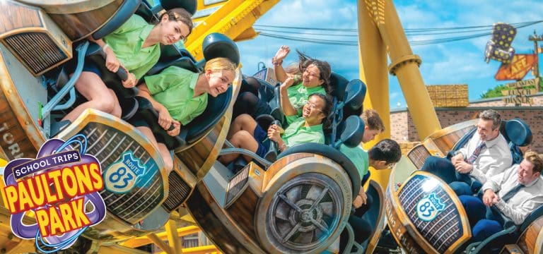 school group including a teacher enjoying a fast moving theme park ride