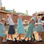 school trip group at an animal enclosure waving hands while having a photo taken
