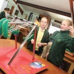 two school students interacting with a theme park exhibition module in a engineering room