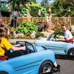 primary school children in mini battery cars on a track at the theme park