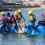 school students on make shift raft on lake paddling