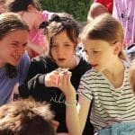 three school pupils in a flower bed filed looking at butterflies