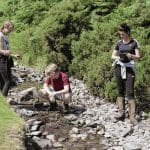 three post 16 school students doing eco river study field work