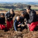 school group up on a hill looking in heather and moss doing field studies