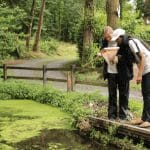 two secondary school pupils with a net looking at its contents from a pond
