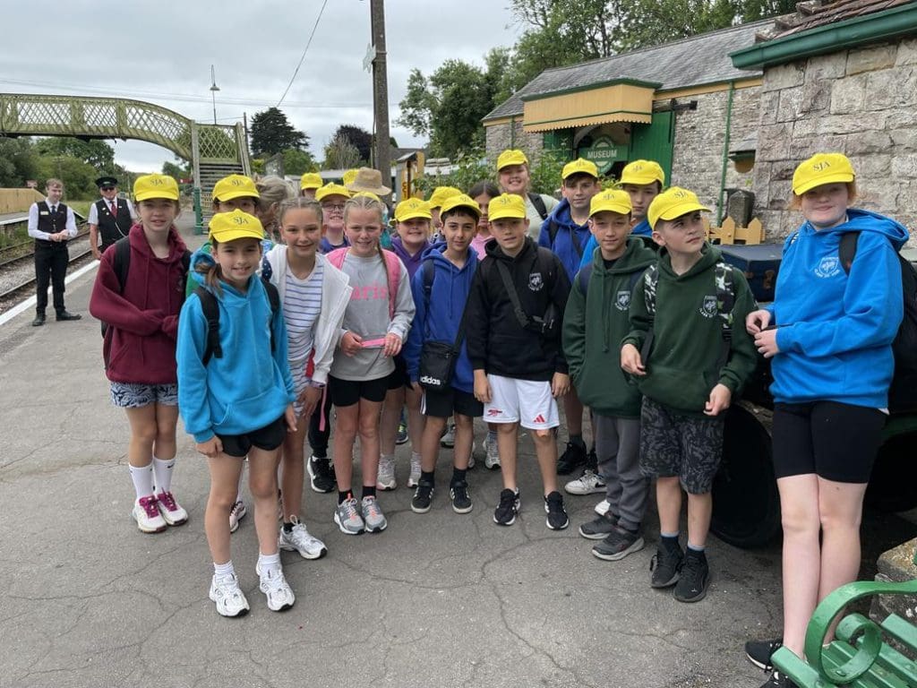 school group having photo taken on a school trip at a heritage railway station