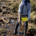 school trip pupil in a stream doing field work to monitor water quality