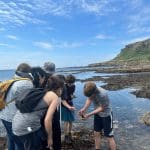 group of school pupils investigating rock pools at the coast