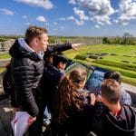 school group with teacher looking at old roman fort and settlement outside