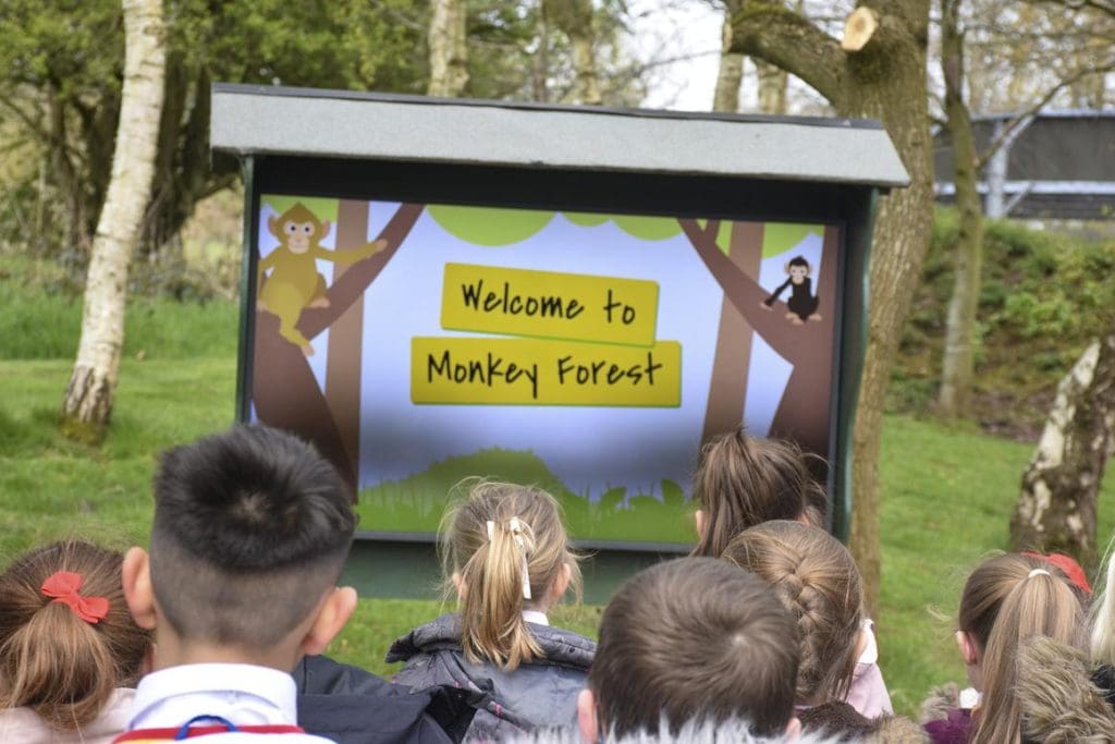 children outside looking at a signed saying welcome to monkey forest
