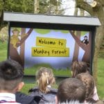 children outside looking at a signed saying welcome to monkey forest