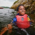 school pupil in a lake with wetsuit and life jacket on