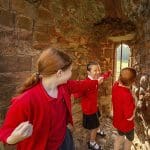 primary school pupils looking out a stone window of a castle wall