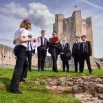 school trip group outside with an educational instructor on a castle tour