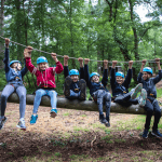 school group in a forest hanging off a rope