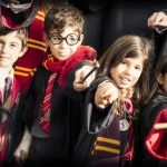 four school pupils with wizard sticks and dressed as harry potter for a group photo