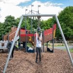 school pupil on swings in an adventure play park outside