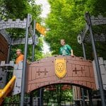 school children playing on an adventure play park themed castle activity frame