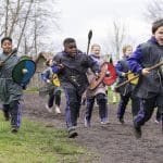 group of school children dressed in Saxon clothes running with shields and spears