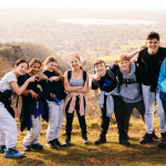 students on top of a hill in the countryside having a photo taken
