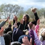 students with their hands up in a field