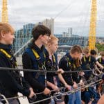 school group standing on top of the O2 in London with safety equipment attached to a safety line