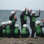 pupils in wetsuits on the beach