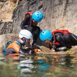 three school pupils in wet suits at the seaside in the water