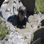 school trip pupil crawling in mud on an assault course