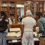 students in an old library room looking at books of anatomy