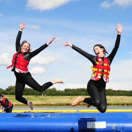 two students jumping off a water slide