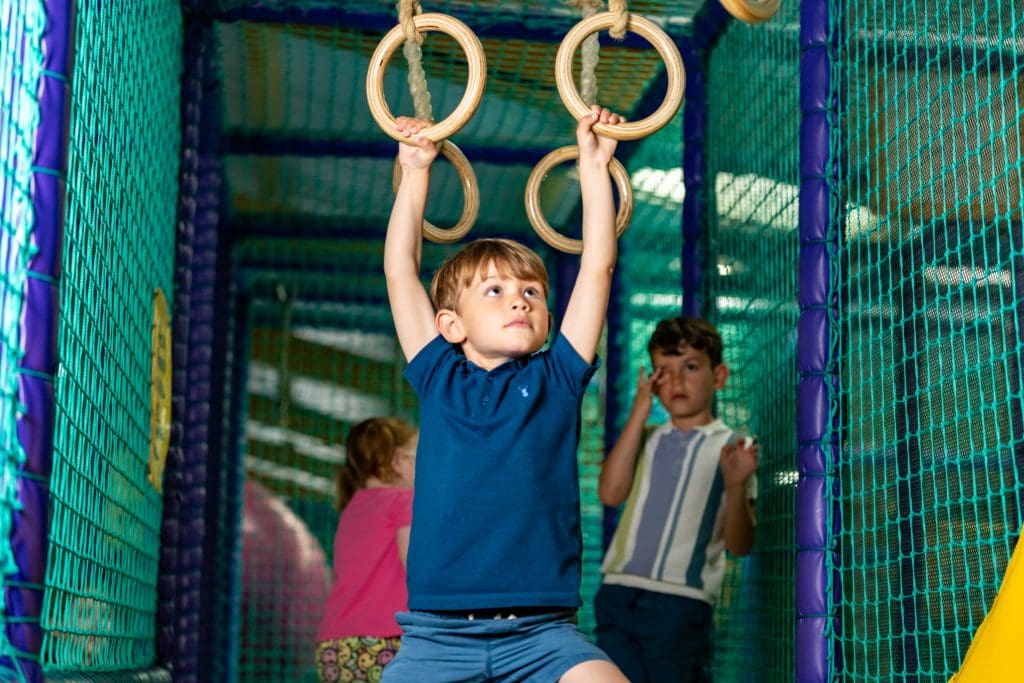 school pupil in an indoor play area on activity rings in the air