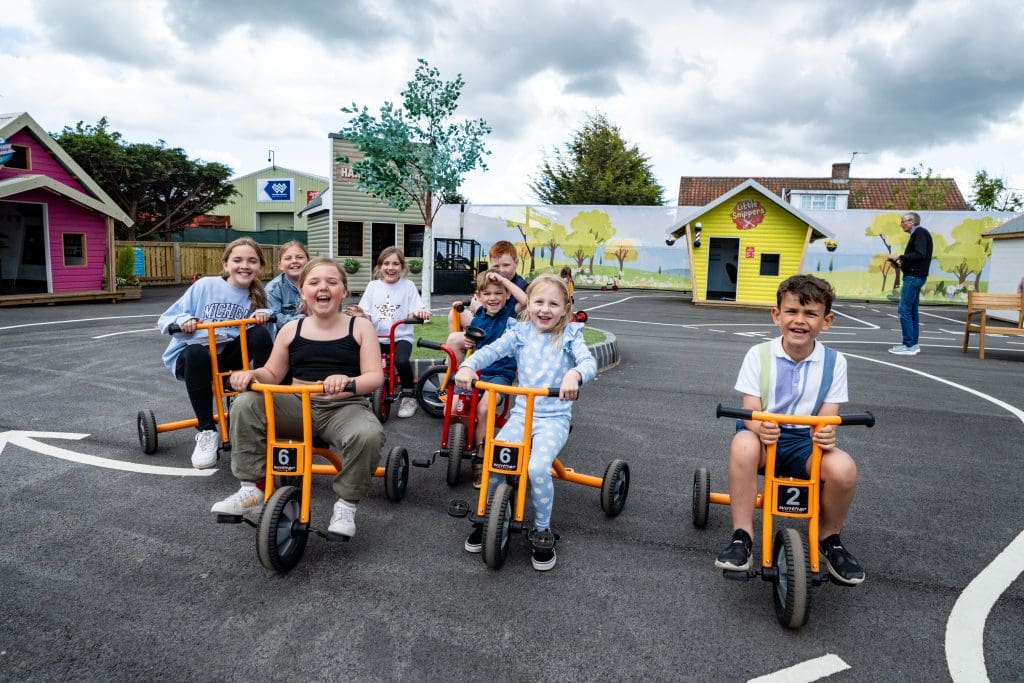 group of primary pupils on small bikes in a play area