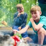 school trip pupils cooking sweet corn over a fire pit