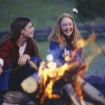 two secondary school trip pupils around a fire cooking marsh mellows