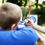 school pupil doing archery on a range