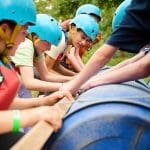 group of students building a raft made of wood and blue plastic barrels