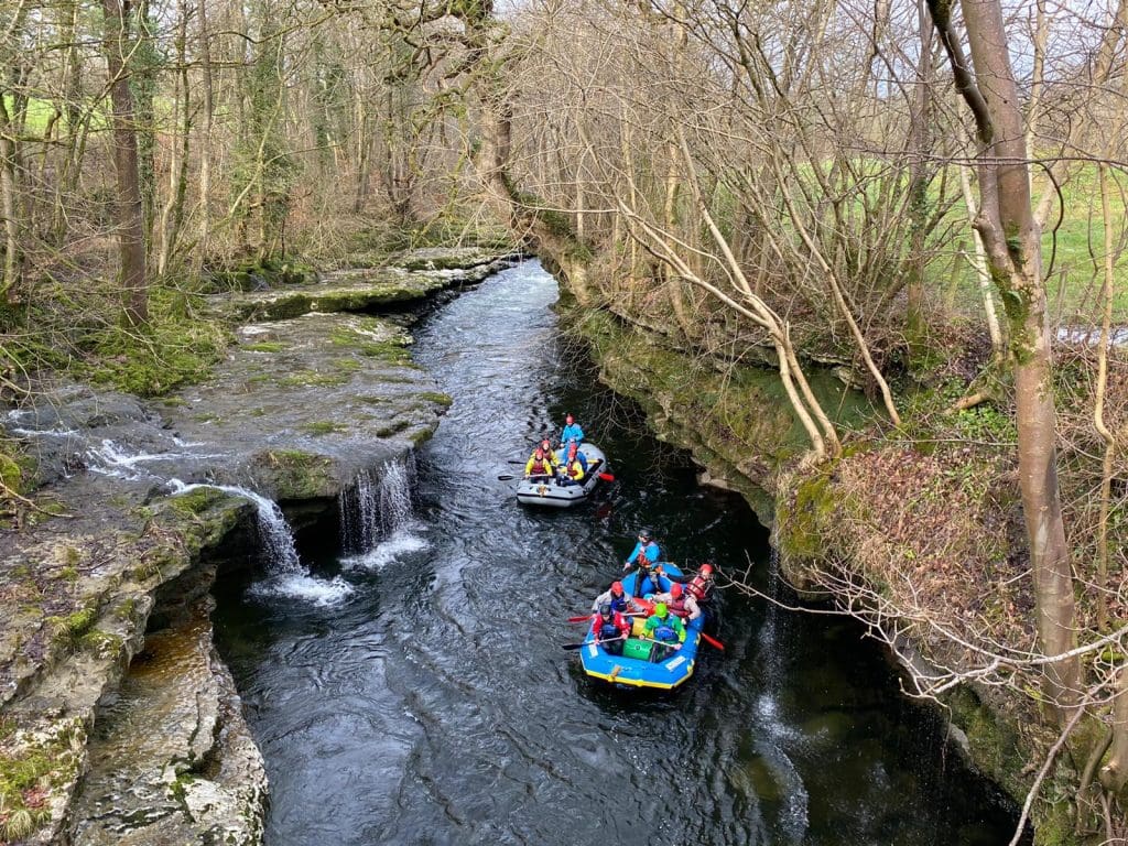 dingys on a river with groups of school pupils in it